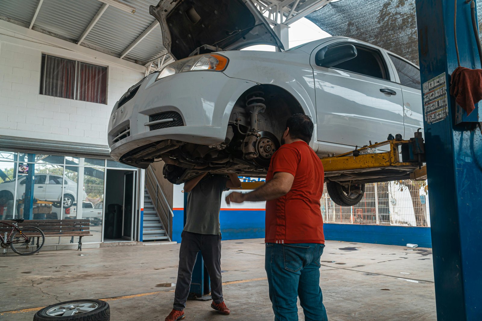 A car on a lift inside a multi-brand service workshop.